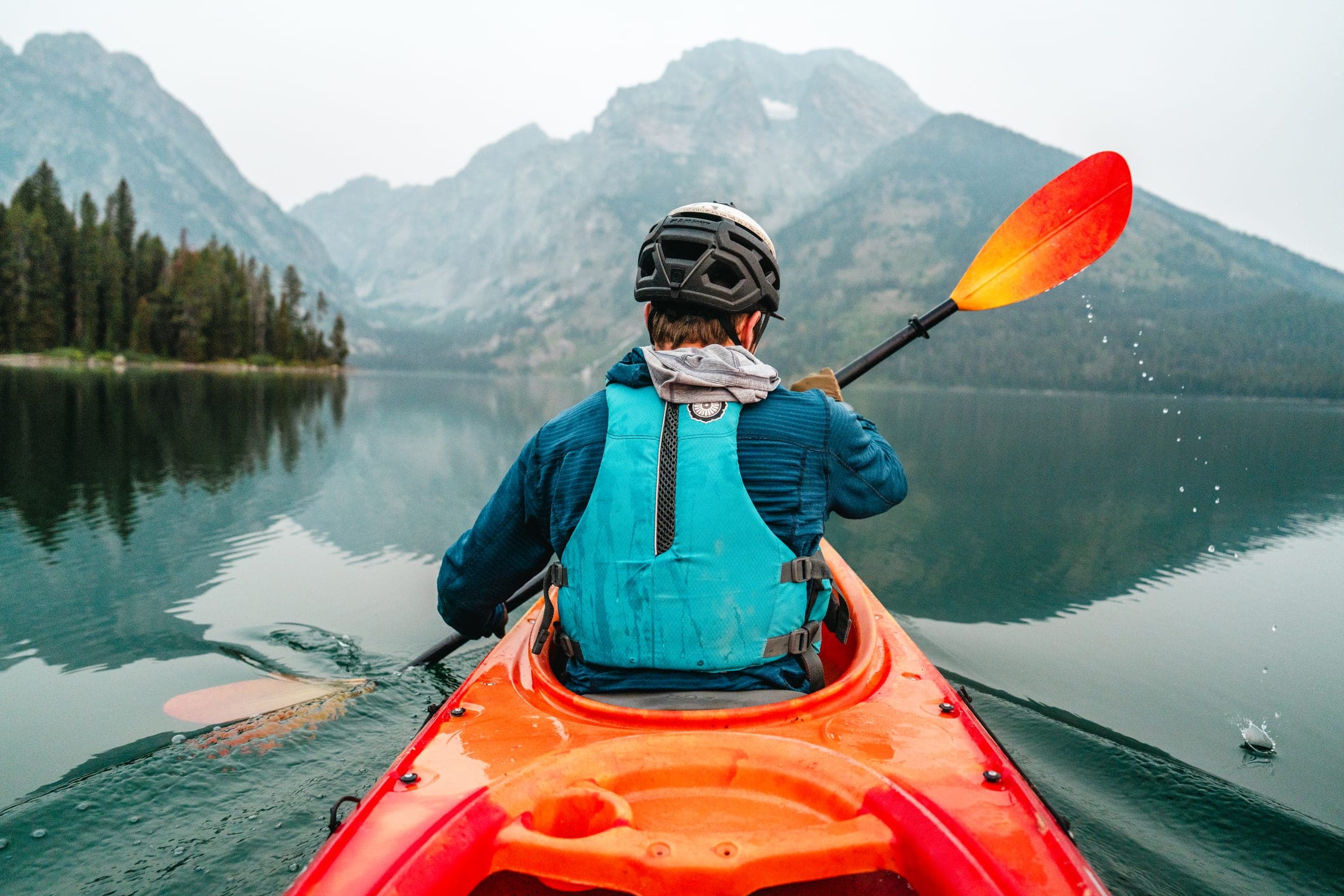 Over-the-shoulder kayak on a glassy Teton lake