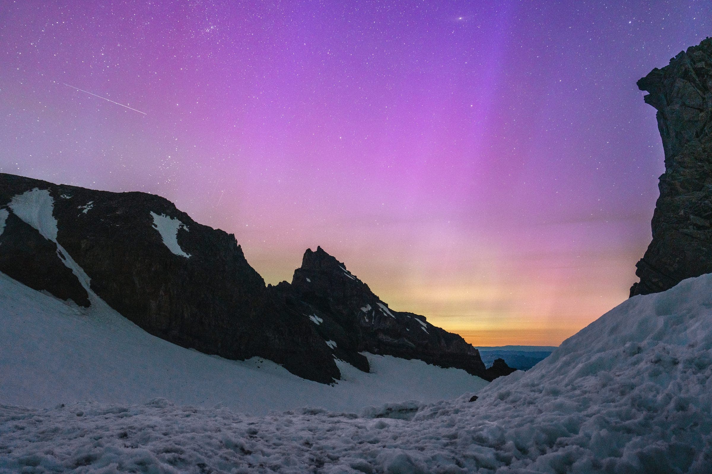 Purple aurora over Rainier's snowfield and black rock