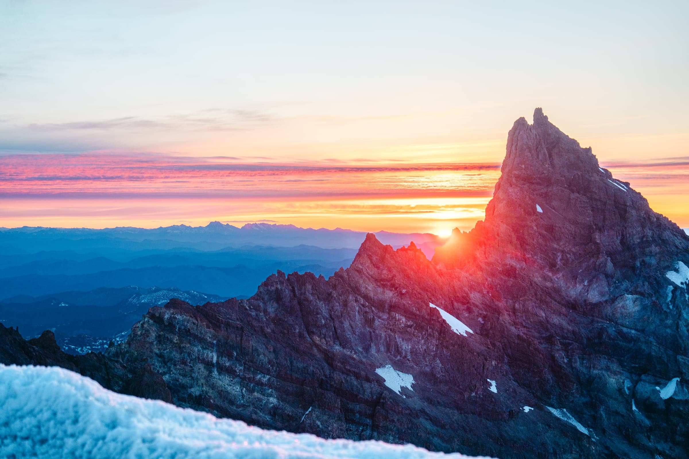 Sunrise igniting a Rainier spire above a sea of cloud